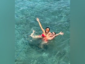 Two friends joyfully swim together in crystal-clear waters, capturing the essence of fun and adventure on a perfect day at sea.