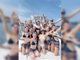 A lively group of friends celebrates on a yacht, showcasing joy and camaraderie perfect for bachelorette parties or summer outings on the water.