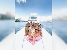 A lively group of friends enjoys a fun day on a yacht, showcasing their stylish swimwear and heart-shaped sunglasses — perfect for summer celebrations on the water.