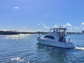 A sleek yacht navigates through sparkling waters under a clear blue sky, showcasing a perfect day for boating adventures.
