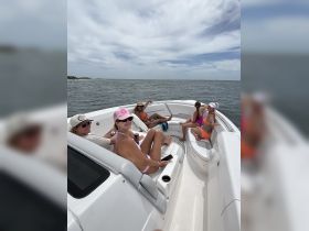 A lively group of friends enjoys a fun day on the boat, relaxing and sipping drinks while soaking up the sun on the water.