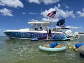 A lively scene featuring the 'SEA-N-DOUBLE' boat with guests enjoying a day on the water, showcasing fun activities and relaxation in a beautiful setting.