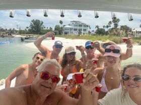 A lively group raises their drinks in celebration aboard a boat, enjoying a fun day at the beach — perfect for parties and gatherings on the water.