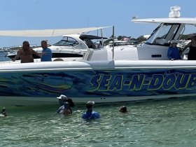 A lively scene with a group enjoying the water around the 'SEA-N-DOUBLE' boat, showcasing fun and camaraderie during a day on the water.