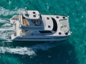 A stunning aerial view of a yacht cruising through crystal-clear turquoise waters, showcasing its elegant design and perfect for luxury charters.