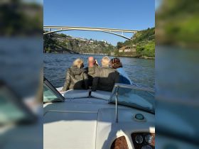 A group of friends enjoys a scenic boat ride on the river, capturing memories with a picturesque bridge in the background — perfect for exploring beautiful waterways.