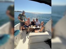 A lively group enjoys a fun day on the water, sharing food and drinks aboard a boat — perfect for social gatherings and celebrations.