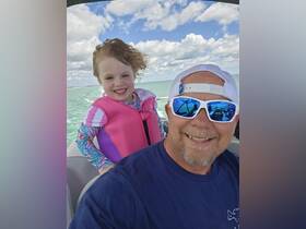 A joyful moment captured on a boat with a smiling child and adult, showcasing the fun of family outings on the water.
