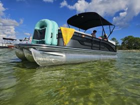A group enjoys a sunny day on a pontoon boat, perfect for relaxing and swimming in clear waters.