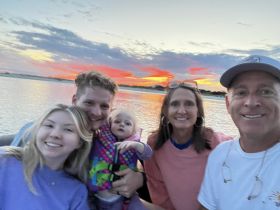 A joyful family captures a sunset selfie on a boat, creating lasting memories during their water adventure.