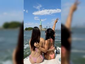 Two friends enjoy a scenic boat ride past the iconic Statue of Liberty, capturing a moment of joy and adventure in New York City.