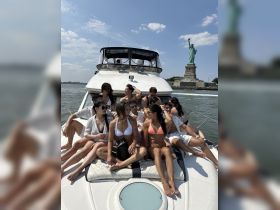 A lively group enjoys a sunny day on a yacht near the Statue of Liberty, perfect for celebrations and memorable outings on the water.