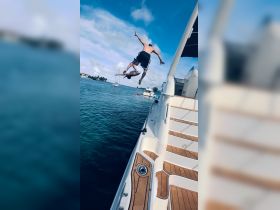Two friends leap off the side of a boat into the water, capturing the thrill of summer fun and adventure on the water.