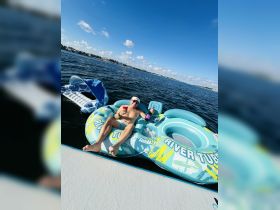 A man enjoys a relaxing day on a river tube with cocktails in hand, surrounded by beautiful water and a sunny sky — perfect for summer fun and leisure.