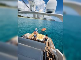 A lively group enjoys a day on the water, engaging in fun activities aboard a boat, with a beautiful coastal backdrop.