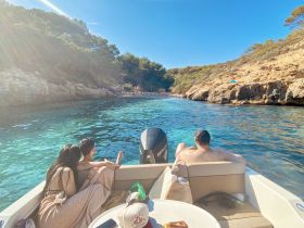 A group enjoys a relaxing moment on a boat, surrounded by stunning turquoise waters and rocky cliffs, perfect for a day of exploration and leisure.