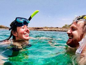 A joyful couple enjoys snorkeling in crystal-clear waters, capturing the essence of adventure and fun in the sun.