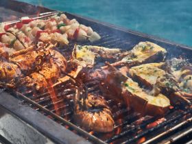 Delicious seafood grilling on a boat, featuring lobster and vegetable skewers — perfect for a gourmet experience on the water.