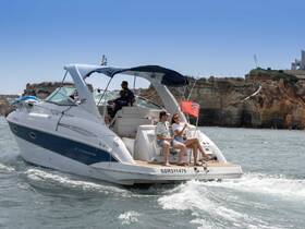 A couple enjoys their time aboard a Crownline boat, celebrating with drinks while cruising along scenic coastal cliffs — a perfect day on the water.