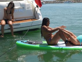 Two friends enjoy a fun paddleboarding session in clear waters, showcasing a lively day on the water with laughter and camaraderie.