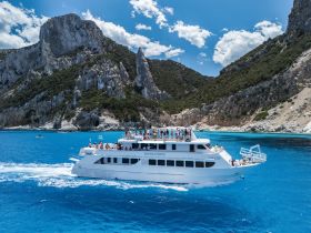 A lively group enjoys a scenic cruise aboard a spacious boat, surrounded by stunning coastal landscapes and vibrant blue waters.
