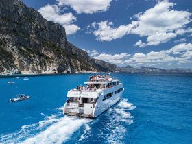 A lively cruise aboard the 'Imperatrice' with guests enjoying the stunning blue waters and scenic cliffs — an ideal setting for unforgettable group adventures.