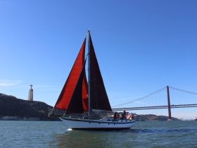 A beautiful sailing experience with a group aboard a boat, showcasing the stunning backdrop of a bridge and a landmark, perfect for sightseeing tours.