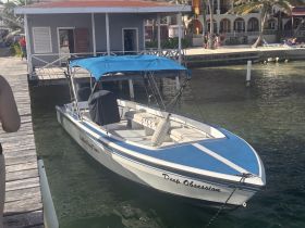 A sleek speedboat named 'Deep Obsession' docked at a waterfront, showcasing its stylish design against a vibrant backdrop of nearby buildings.