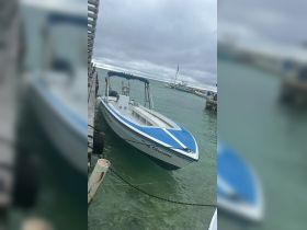 A sleek speedboat named 'Deep Obsession' docked in calm waters, showcasing its vibrant blue accents and ready for adventure.