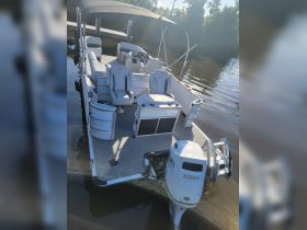 An interior view of a spacious pontoon boat featuring comfortable seating and a well-equipped helm, perfect for leisurely outings on the water.