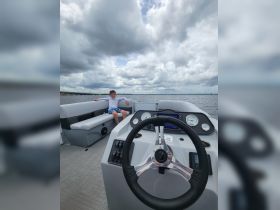 A young boy relaxes on the seating area of a boat, showcasing the helm and spacious interior — perfect for family outings on the water.