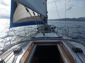 A stunning view from the bow of a sailboat, showcasing the sails and the shimmering sea as it glides through the water, perfect for sailing enthusiasts.