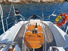 A beautifully set dining area on a sailboat featuring delicious food and drinks, perfect for enjoying a meal while cruising on the water.