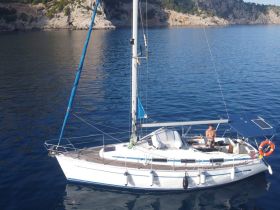 A man enjoys a peaceful moment aboard a sailboat, navigating through serene waters surrounded by stunning cliffs — perfect for sailing enthusiasts and adventure seekers.
