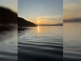 A stunning sunset reflects on the calm waters, creating a picturesque scene perfect for evening boat trips or romantic getaways.