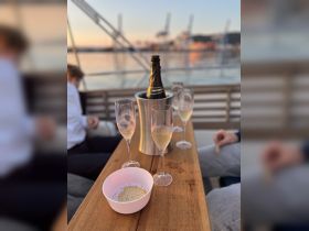 A beautifully set table on a boat featuring champagne and snacks, perfect for a relaxing evening on the water.