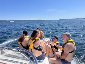 A lively group enjoys a sunny day on the water, sharing drinks and laughter aboard a boat — perfect for summer outings and celebrations.
