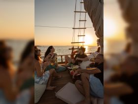 A lively group enjoys a sunset gathering on a boat, complete with delicious food and drinks, creating the perfect atmosphere for celebration and relaxation on the water.