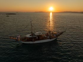 An aerial view of a boat at sunset, with guests enjoying the serene waters — a perfect setting for memorable evening cruises.