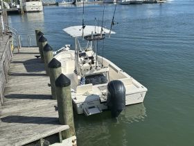A center console boat docked at the marina, showcasing its sleek design and fishing equipment, perfect for a day on the water.