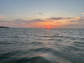 A serene sunset over the water, capturing the tranquil beauty of the coastline — perfect for peaceful evening boat rides.