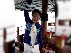 A joyful angler proudly displays his catch aboard a boat, showcasing the thrill of fishing adventures on the water.