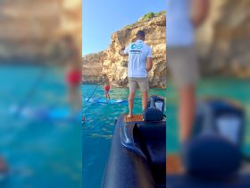 A fun day on the water featuring paddleboarding and swimming, showcasing an exciting group experience in a stunning coastal setting.