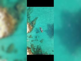 Aerial view of a boat navigating through crystal-clear turquoise waters, showcasing the stunning marine landscape and vibrant underwater scenery.