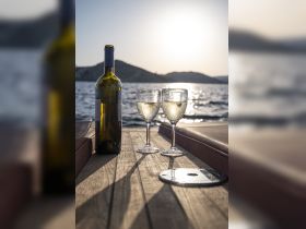 A serene setting featuring a bottle of wine and two glasses on a boat deck, perfect for enjoying a sunset cruise or a relaxing day on the water.