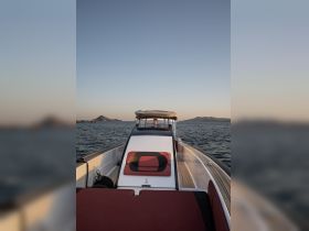 A view of the helm area inside a sleek boat, showcasing comfortable seating and a captain at the controls, perfect for enjoying scenic cruises on the water.