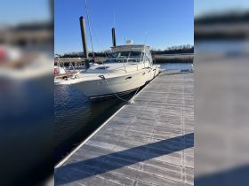 A sleek speedboat docked at a marina, showcasing its elegant design against a clear blue sky — perfect for day trips and fishing adventures.