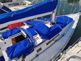A detailed view of a sailboat with blue covers, docked and ready for sailing. The vibrant colors and clean lines highlight its sleek design.