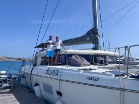 A couple poses on the deck of the BELIVISTA yacht at the dock, showcasing a perfect moment before setting sail on their maritime adventure.