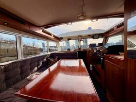 Interior view of a spacious boat cabin featuring a polished wooden table and helm area, perfect for relaxing and navigating on the water.